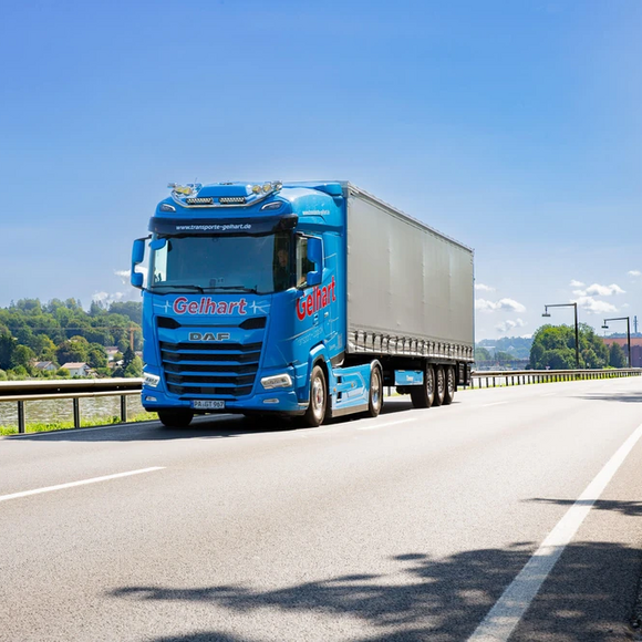 Ein blauer LKW der Spedition Gelhart fährt auf einer Straße