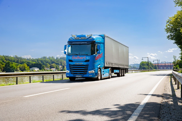 Ein blauer LKW der Spedition Gelhart fährt auf einer Straße